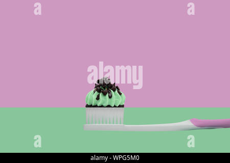 Spazzolino da denti con tortine su due colori rosa e verde, stile minimal. Foto Stock