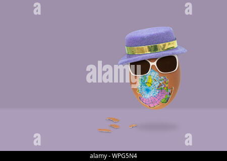 L'uovo sgusciato ha un globo all'interno con occhiali e il cappello vola su sfondo viola. concetto di pasqua. Foto Stock