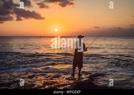 Pescatore pesci nel mare al tramonto Foto Stock