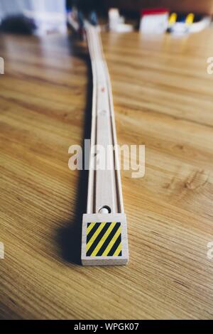 Primo piano verticale selettivo di una pista giocattolo per auto da corsa su una superficie di legno Foto Stock