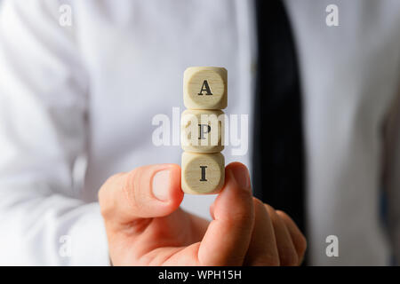 Imprenditore azienda tre dadi con il segno di API in una immagine concettuale. Foto Stock