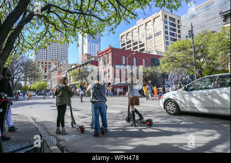 La gente ride e-scooter sulla Sesta Strada di Austin in Texas durante SXSW Festival in marzo 2019. Foto Stock