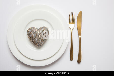 Anniversario di matrimonio la cena messa in tavola, oro forchetta e coltello sul set di bianco di piatti isolati, sfondo bianco, vista dall'alto Foto Stock