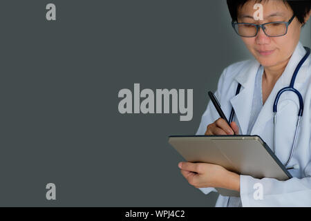 Medico con uno stetoscopio e labtop su sfondo grigio con copia spazio per scrivere. Foto Stock