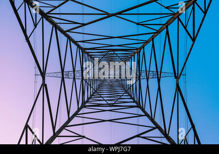 Il worm-eye view di un pilone di potenza contro un bel cielo colorato Foto Stock