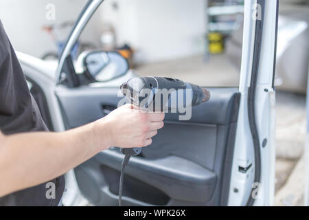 Lavoratore rimozione auto finestra foglio di pellicola utilizzando la pistola ad aria calda. Foto Stock