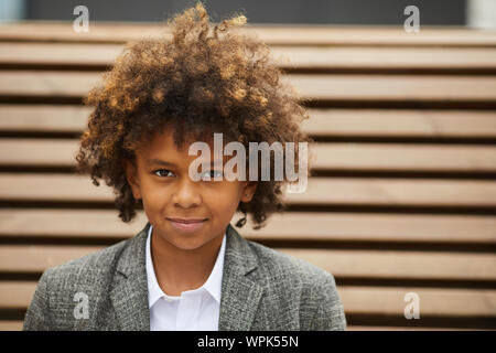 Ritratto di Allegro ragazzo africano con capelli ricci guardando la fotocamera all'aperto Foto Stock