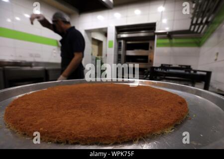 Amman, Giordania. 8 Sep, 2019. Un baker rende kunafa presso un negozio di Amman, Giordania, Sett. 8, 2019. Kunafa è un tradizionale arabo dolce fatto di formaggio, farina, sciroppo, e aggiunto con i dadi come ingredienti. Credito: Mohammad Abu Ghosh/Xinhua/Alamy Live News Foto Stock