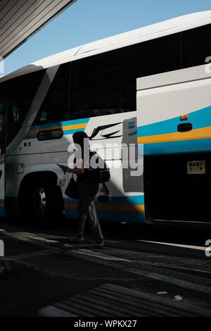 MATSUYAMA, Giappone - Lug 25, 2019: un colpo verticale di una persona vicino a un bianco tour bus con tronco aperto Foto Stock