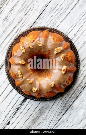 Deliziosi, zucca Spice Bundt Cake satinato marrone con glassa di zucchero e noci forno una tavola in legno rustico sfondo. Vista dall'alto in basso. Foto Stock