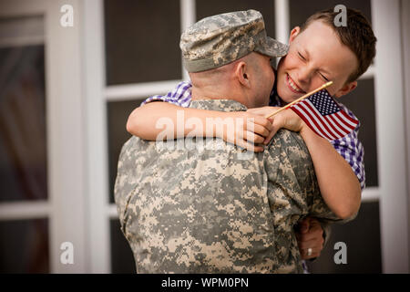 Metà uomo adulto vestito in uniforme militare è accolto da suo figlio. Foto Stock