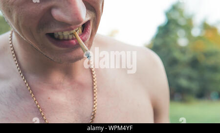 Il giovane di fumare la marijuana medica giunto all'esterno. Il giovane uomo fumare cannabis blunt, close-up. La cannabis è un concetto di medicina di erbe. Foto Stock