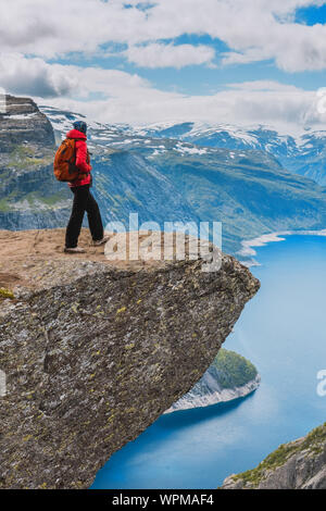 Sportivo da donna in posa sul Trolltunga. Felice escursionista godere del bellissimo lago e buone condizioni meteorologiche in Norvegia. Foto Stock