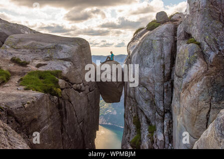 Turista su Kjeragbolten mani alzate viaggi in Norvegia Kjerag montagne extreme vacanze turismo avventura felice emozioni concetto di successo Foto Stock