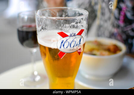 Pranzo pomeridiano a Paris cafè sul marciapiede con un bicchiere di Kronenbourg 1664 birra, un bicchiere di vino rosso e la zuppa di cipolla fonduta. Foto Stock