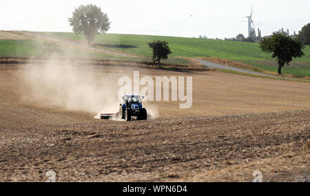 06 settembre 2019, in Sassonia, Grimma: un trattore viaggia con un erpice e abbondanza di polvere whirled fino al di sopra di un campo vicino a Grimma. Foto: Jan Woitas/dpa-Zentralbild/ZB Foto Stock