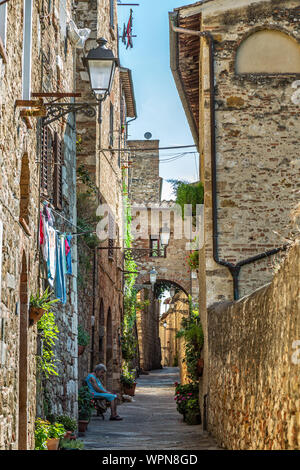 Vecchia donna seduta in un vicolo stretto a Colle Val d'elsa, toscana, Italia Foto Stock