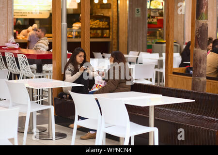LIMA, Perù - Luglio 23, 2013: Unidentified giovane donna seduta con telefoni cellulari su banco nel food court del centro commerciale Larcomar Foto Stock