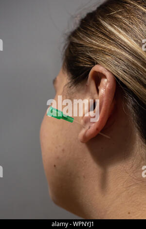 In prossimità di una ragazza bionda ottenendo il suo orecchio forato Foto Stock