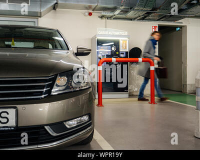 Parigi, Francia - Dic 15, 2017: Silhouette di donna lasciando Caisse Automatique parcheggio automatizzato di macchine di pagamento all'interno Parcheggio sotterraneo accanto al vicino auto parcheggiata Foto Stock