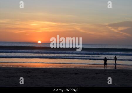 Silhouette di persone sulla spiaggia con una bella cielo sullo sfondo Foto Stock