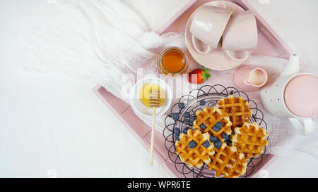 Moderno blush rosa vassoio colazione con cialde, miele e frutta con copia spazio. Foto Stock