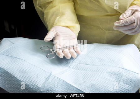 Chirurgo accetta emostatico detenute nel corso drappeggiato sterile tavolo Mayo. Foto Stock