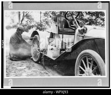 Uomo che fissa il pneumatico su una Buick roadster al di fuori della libertà, in un viaggio attraverso Upstate New York Foto Stock