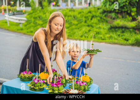 Madre e figlio turisti trattiene il Loy Krathong nelle sue mani ed è in procinto di avviare nell'acqua. Loy Krathong festival, la gente compra i fiori e Foto Stock