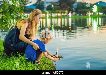 Madre e figlio turisti trattiene il Loy Krathong nelle sue mani ed è in procinto di avviare nell'acqua. Loy Krathong festival, la gente compra i fiori e Foto Stock