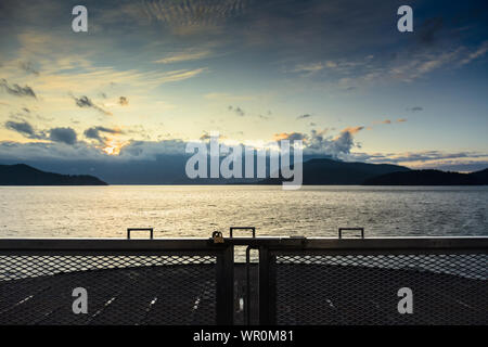 Alba sull'oceano e sulle montagne dalla parte anteriore della vettura di traghetto deck, direzione Est da Gibsons verso Vancouver, Canada. Foto Stock