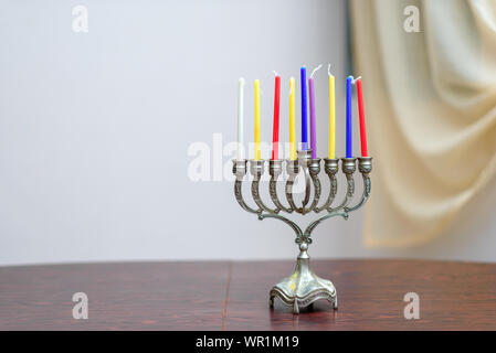 Festa ebraica Hanukkah sfondo con il menorah e candele colorate sul tavolo di legno in casa. Accogliente immagine menorah pronto per l'illuminazione. Foto Stock