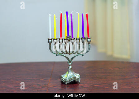 Festa ebraica Hanukkah sfondo con il menorah e candele colorate sul tavolo di legno in casa. Accogliente immagine menorah pronto per l'illuminazione. Foto Stock