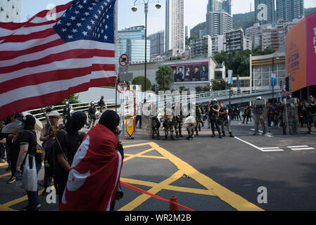 Hong Kong, Cina. 08 Sep, 2019. Manifestanti ondata di Hong Kong e bandierine americane come polizia guardare da fino alla strada durante la dimostrazione.Migliaia di manifestanti hanno marciato per gli Stati Uniti Consolato Generale a sostegno della Hong Kong diritto umano agisce. Manifestanti hanno sventolato bandierine americane, esposti vari cartelli e gridato slogan per chiedere il coinvolgimento degli Stati Uniti. Alla fine la violenza scoppiata come manifestanti vandalizzato alcune stazione MTR di entrate, e la polizia ha in seguito effettuato una operazione di dispersione. Credito: SOPA Immagini limitata/Alamy Live News Foto Stock