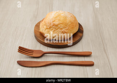 Pane di zucchero melon pan su piastra in legno coltello forcella closeup isolato sul tavolo Foto Stock