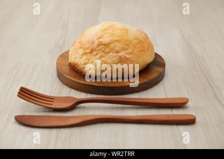 Pane di zucchero melon pan su piastra in legno coltello forcella closeup isolato sul tavolo Foto Stock