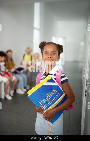 Carino di carnagione scura ragazza con i libri mentre in piedi a scuola Foto Stock