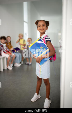 Di carnagione scura ragazza indossando sneakers bianco in piedi vicino gli armadietti Foto Stock