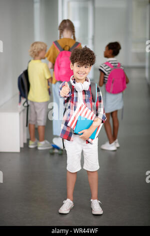 Curly dai capelli scuri boy feeling positivo a scuola Foto Stock