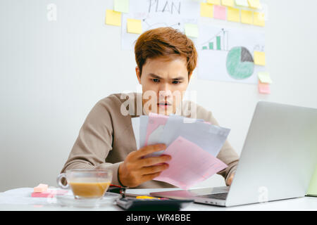 Scioccato uomo con alcuni documenti sul suo ufficio Foto Stock