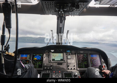 Elicottero cabina con i piloti che volano sopra le Isole Faroe. Danimarca Foto Stock