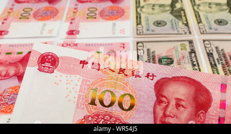 100 cinese Yuan bill close up immagine con piano in dollari US e altre note di Yuan sullo sfondo. Foto Stock