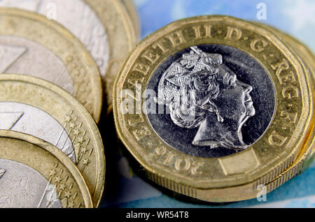 Pila di British pound monete accanto ai caduti la pila di monete in euro. Foto macro. Foto Stock