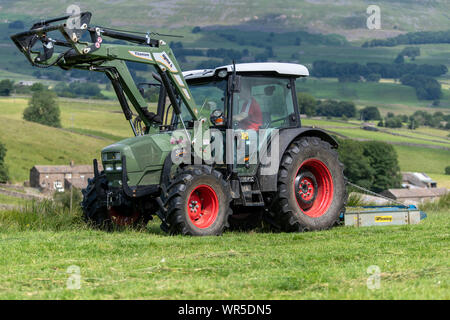 Topping erba ricoperta su un altopiano di pascolo con un trattore Hurlimann e un pascolo di Fleming topper. North Yorkshire, Regno Unito. Foto Stock