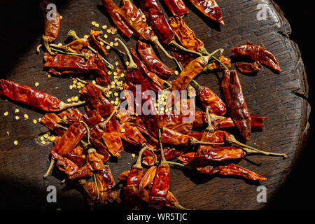 Essiccato intero peperoncino piccante con semi giacente nel fascio di luce solare Foto Stock