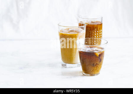 Caffè ghiacciato con la panna e la vaniglia in vari occhiali su sfondo bianco. Summer cocktail o dessert Foto Stock
