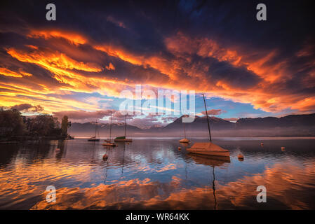 Alba sul lago di Thun in Svizzera con le nubi rosse e riflettendo sulla superficie dell'acqua. Foto Stock