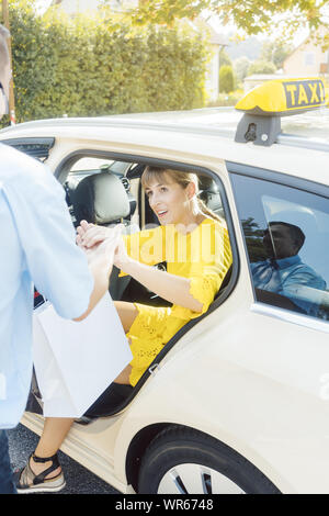 La donna uscendo di taxi e il conducente aiutandola Foto Stock