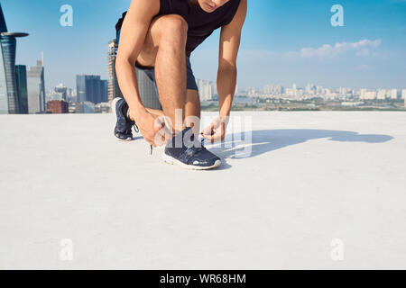 Bella legatura atleta suoi lacci delle scarpe in una giornata di sole Foto Stock