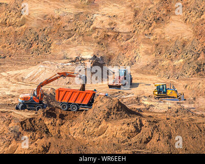 Caricatore escavatore il carico macchina dumper in cantiere e di scavo caricatore su ruote per impieghi pesanti attrezzature da costruzione parcheggiato a buca di sabbia. Foto Stock